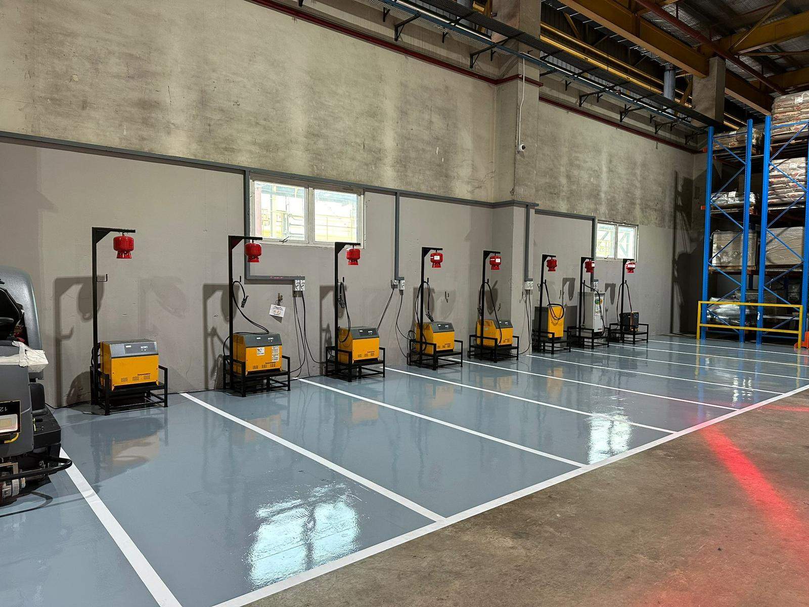 Row of forklift battery charging stations with automatic fire extinguishers mounted above each charger