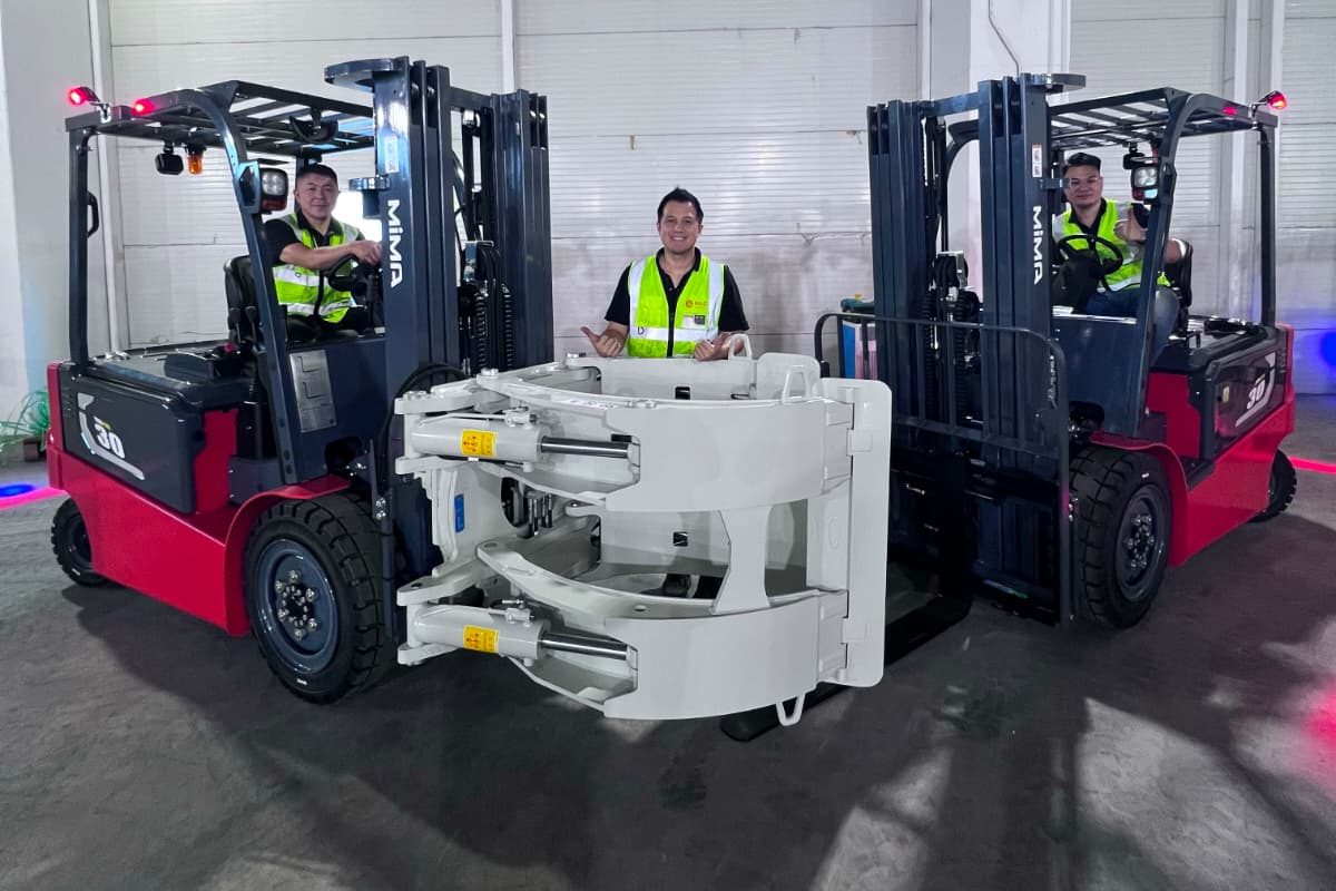 A paper roll clamp fitted to a MiMA 3 tonne electric forklift, with M&C technicians, at handover in Singapore